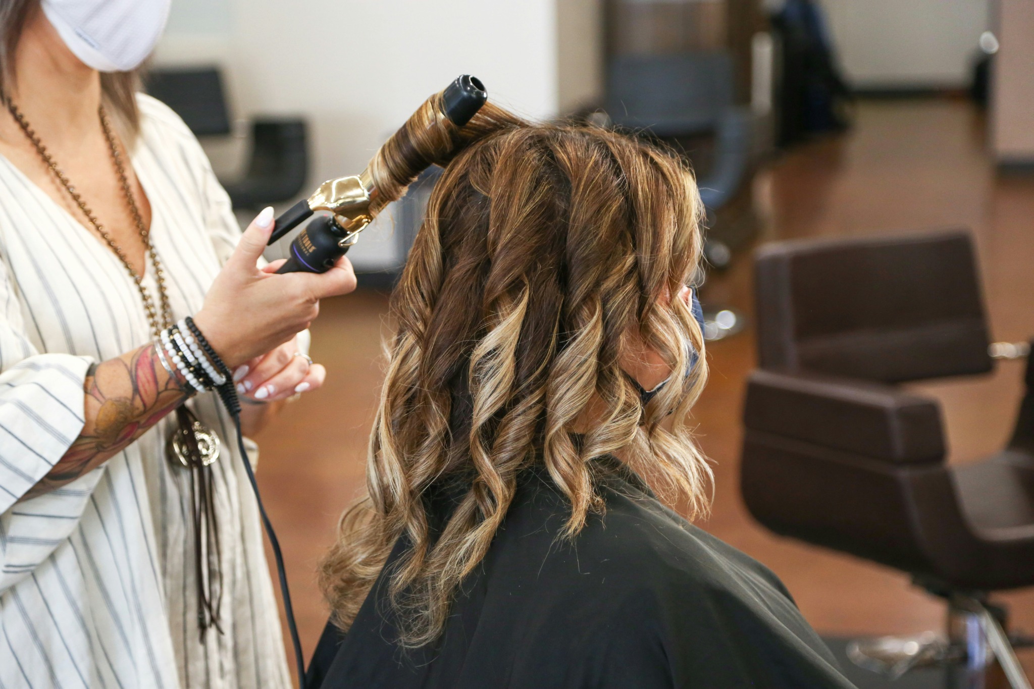 Stylist curling and shaping a client’s hair